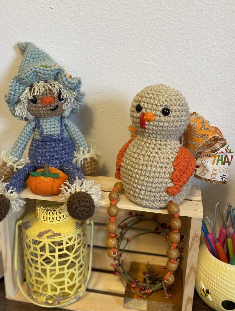 a crocheted turkey and a crocheted scarecrow.