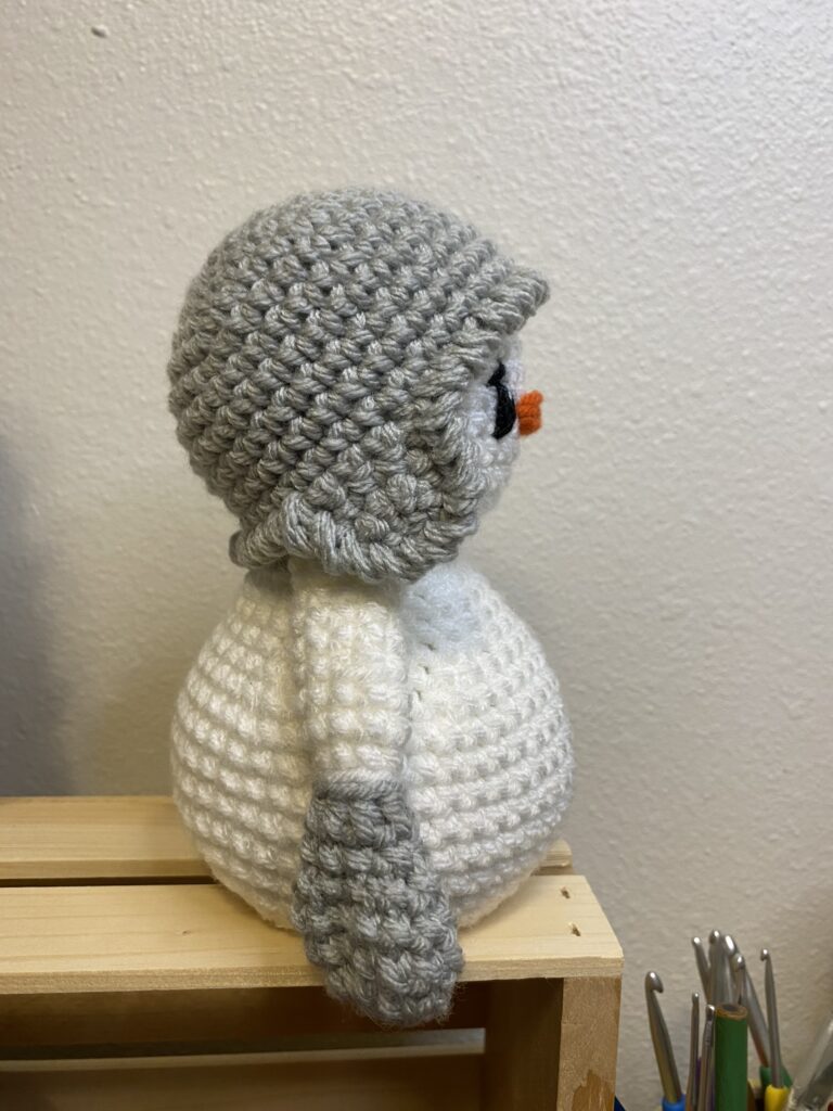 a crocheted snowman wearing a earflap beanie