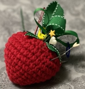 crocheted strawberry pincushion with a ribbon top