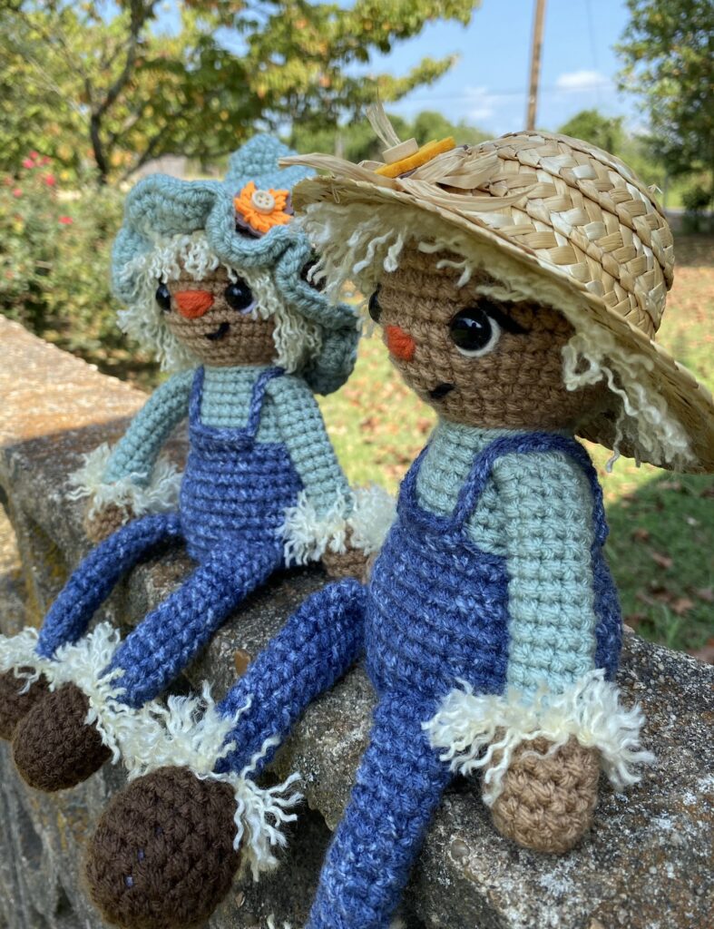 crocheted scarecrow in a straw hat wearing overalls
