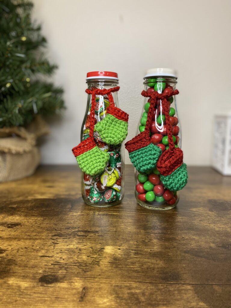 Tiny crocheted mittens wrapped around a Starbucks Frappuccino bottle with candy in it